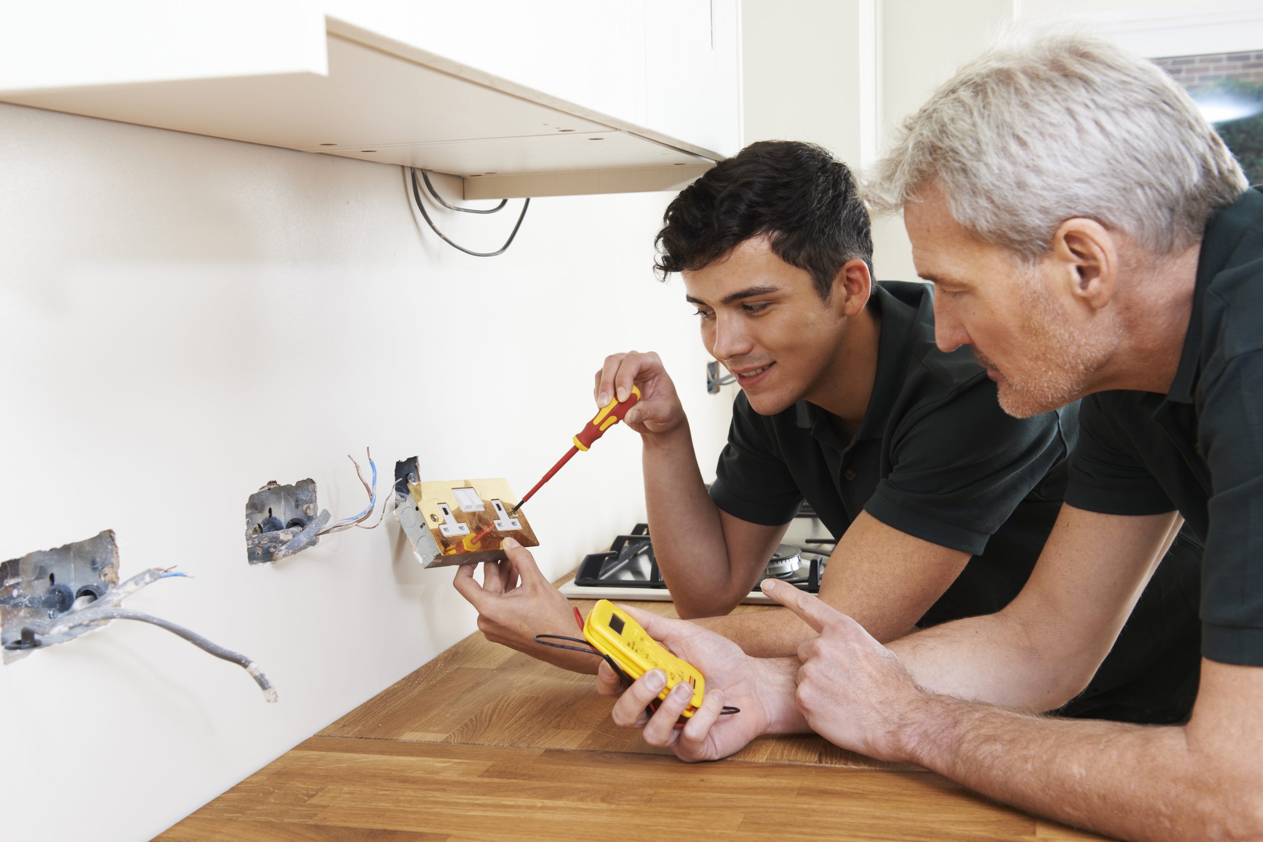 Electrician With Apprentice Working In New Home